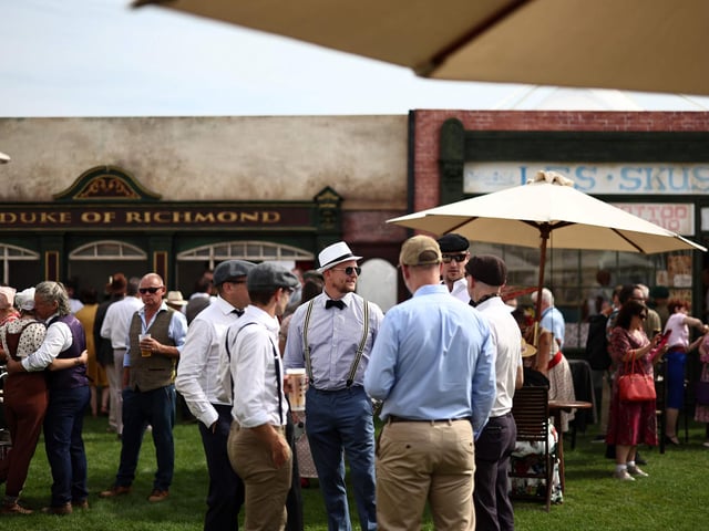 People wearing period clothing attend the opening day of Goodwood Revival at the Goodwood Motor Circuit in Chichester on September 8, 2023. The only historic motor race meeting to be staged entirely in a period theme, Goodwood Revival is an immersive celebration of iconic cars and fashion. (Photo by HENRY NICHOLLS / AFP) (Photo by HENRY NICHOLLS/AFP via Getty Images)