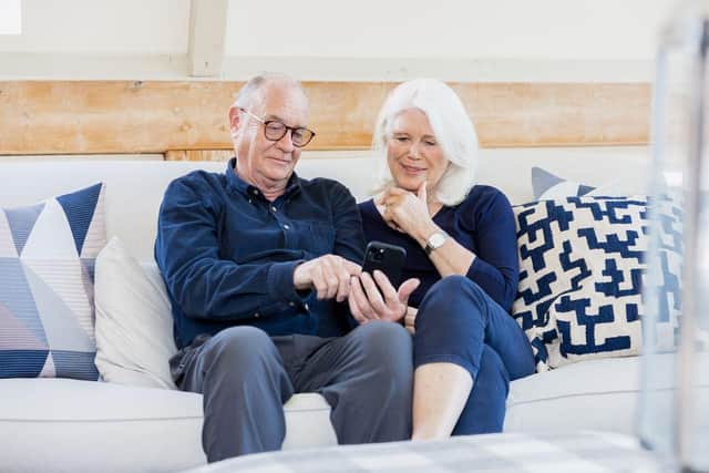 A married couple sitting on the sofa looking at a smart phone