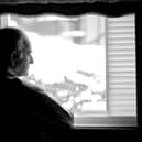 Lonely senior man looking at the window