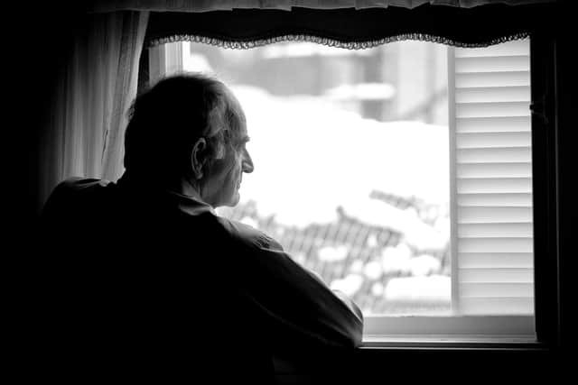 Lonely senior man looking at the window