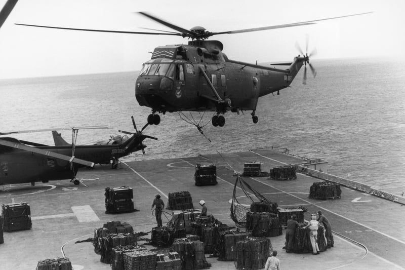 A Sea King helicopter hovering above HMS Hermes to airlift ammunition for redistribution to other ships in the convoy, April 1982.