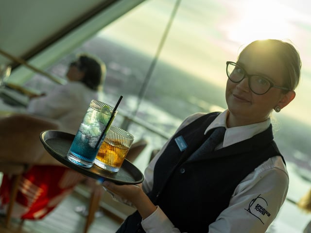 A Sky Bar staff member bringing cocktails - including the signature blue 'Spinnaker Tower' drink - to guests.