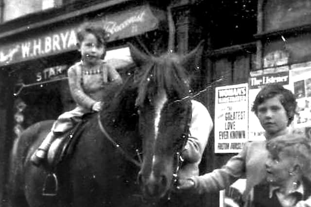 Lee Bryant on a pony outside his grandfather's paper shop WH Bryant's in Charlotte Street, Portsmouth.