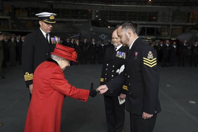 Queen Elizabeth II presents the 15 years long service and good conduct medal to Petty Officer Matthew Ready (right), during a visit to HMS Queen Elizabeth at HM Naval Base, Portsmouth, ahead of the ship's maiden deployment. The visit comes as HMS Queen Elizabeth prepares to lead the UK Carrier Strike Group on a 28-week operational deployment travelling over 26,000 nautical miles from the Mediterranean to the Philippine Sea. Picture: Steve Parsons/PA Wire