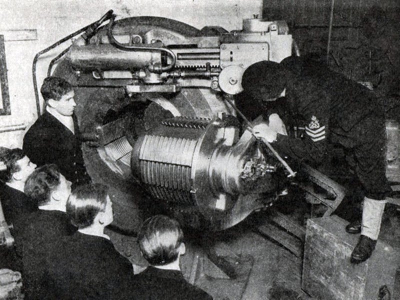 Young officers at HMS Excellent, Whale Island the Navy's gunnery school. They are being shown the finer points of a breech and breech block of a 15 inch gun. Young junior seaman Thake was hauled into the breech to de-copper it.