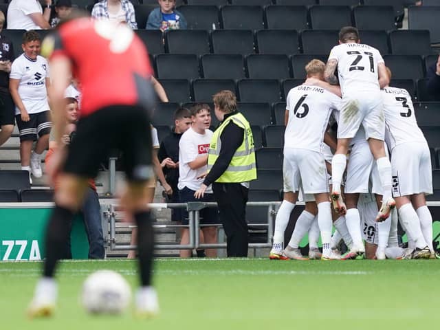 The MK Dons players mob Ethan Robson following his decisive goal against Pompey.  Picture: Jason Brown
