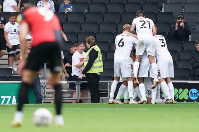 The MK Dons players mob Ethan Robson following his decisive goal against Pompey.  Picture: Jason Brown