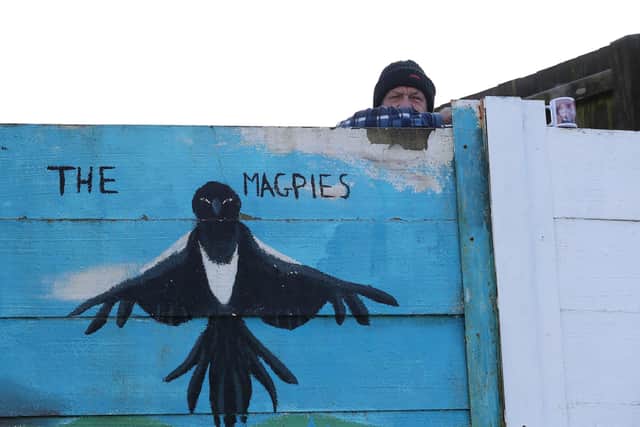 A spectator watches from behind a fence during Chorley's win against Derby. Picture: Martin Rickett/PA Wire.