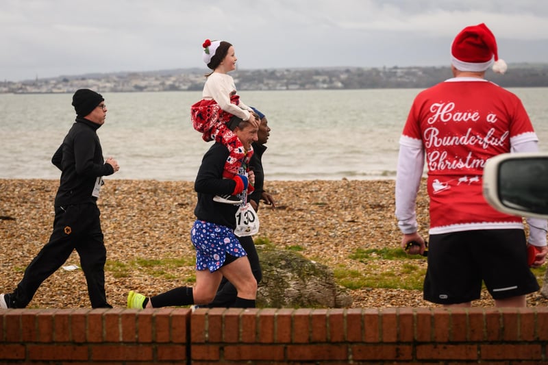 A young runner catches a lift on the home straight of the Christmas Pud 5k at Stokes Bay, Gosport.