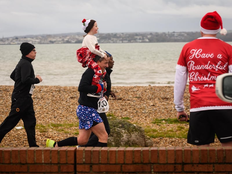 A young runner catches a lift on the home straight of the Christmas Pud 5k at Stokes Bay, Gosport.