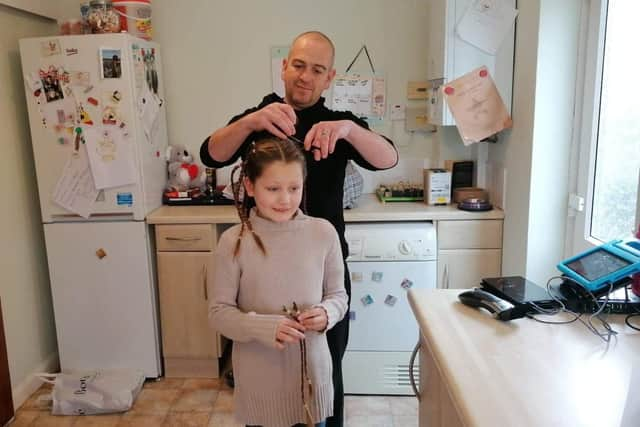 Dad Paul Owen in the middle of cutting Katelyn's hair