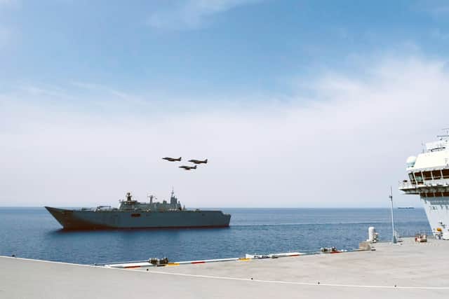 A set of Harrier jump jets soar past HMS Prince of Wales during her trip to Spain.