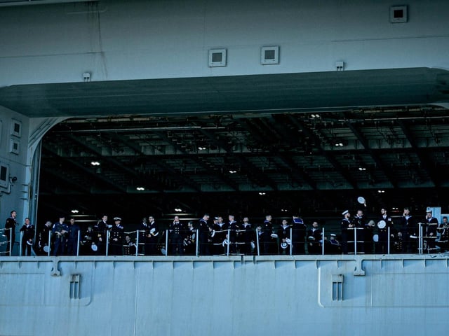 Sailors waving at family and friends waiting for them at the jetty.