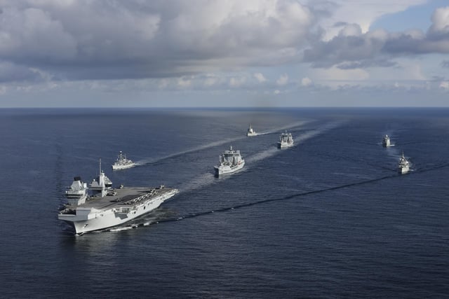The UK CARRIER STRIKE GROUP during Exercise Joint Warrior. Aerial imagery of the UKCSG Task Group taken from a Merlin Mk2 of 814 Naval Air Squadron.Viewed from the front - HMS Prince of Wales; Row 2 (L-R) – HMS Portland, RFA Tidesurge, HMCS Charlottetown; Row 3 (L-R) – SNS Cristόbal Colόn, RFA Tidespring, HMDS Niels Juel.