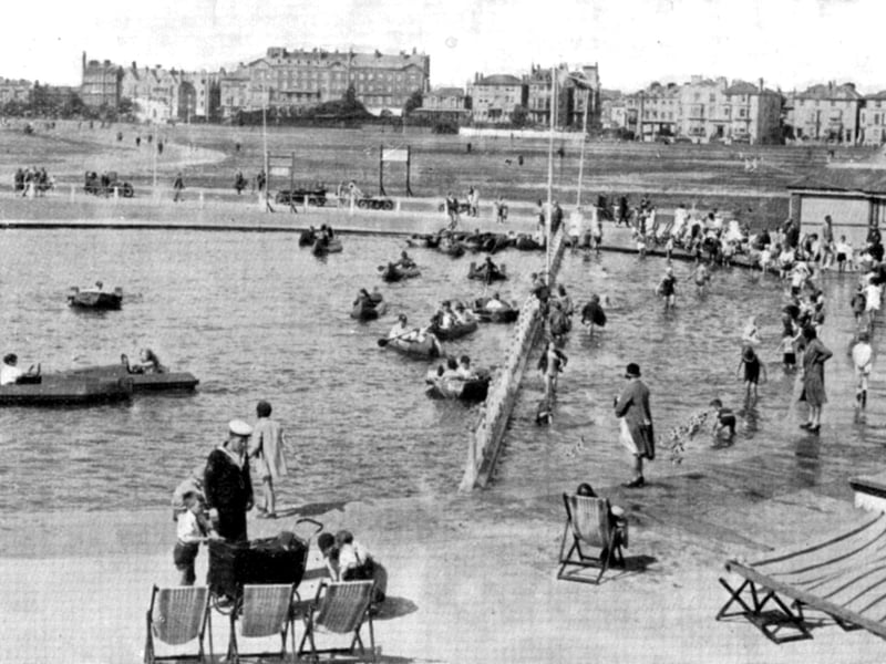 The children's boating and bathing pool, near Southsea Castle. It was constructed so that even the tiniest children could paddle. To the forefront can be seen a sailor in square rig, home on leave perhaps with the family. In the distance the Queens Hotel overlooks Southsea common. The site is now Blue Reef Aquarium.