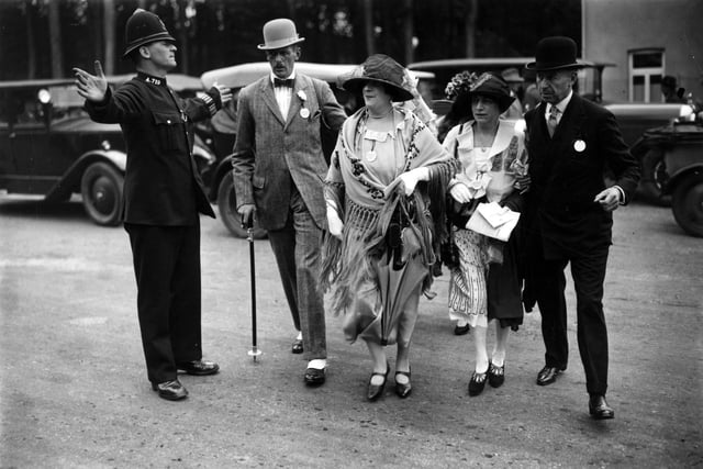 27th July 1926:  A poloiceman helping a group of racegoers crossing the road as they arrive at Goodwood.  (Photo by Topical Press Agency/Getty Images)