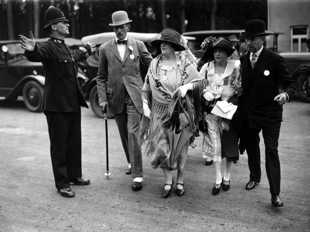 27th July 1926:  A poloiceman helping a group of racegoers crossing the road as they arrive at Goodwood.  (Photo by Topical Press Agency/Getty Images)