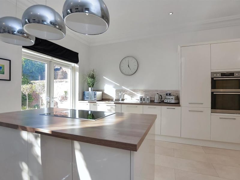 Another part of the family kitchen. It boasts a comprehensive range of high-class, modern cabinets, wall and base units, cupboards and drawers, plus a central island housing a four-ring induction hob, while integrated appliances include an eye-level, double oven, fridge/freezer and dishwasher.