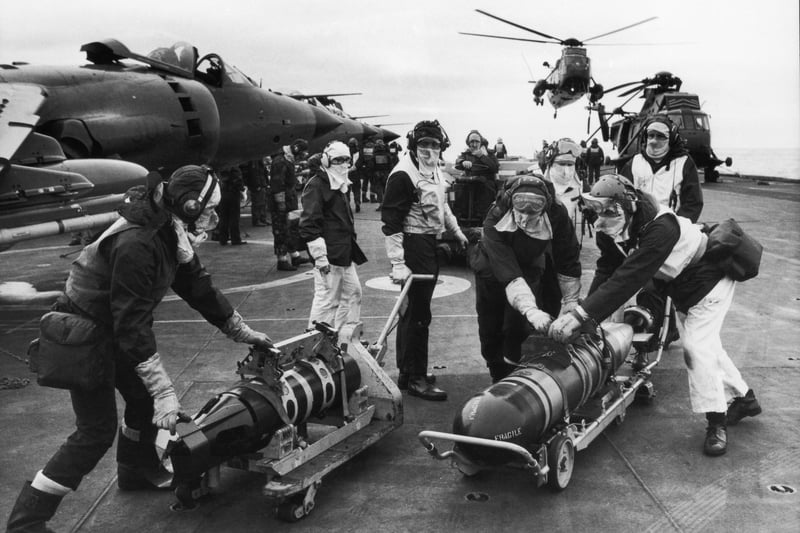 Armourers moving torpedoes on the flight deck of HMS Hermes during the Falklands conflict, May 1982. The torpedoes are to re-arm Sea King helicopters to counter the threat from Argentinian submarines.