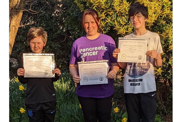 William Cage with his mum Claire and brother Robson who all ran 28 miles in 28 days for Pancreatic Cancer UK and received a NOZOMI Award of Recognition