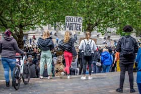 Three friends listen to one of the demonstration's speakers gathered on the steps of the Civic Offices, as the crowd stretches to the back of Guildhall Square.