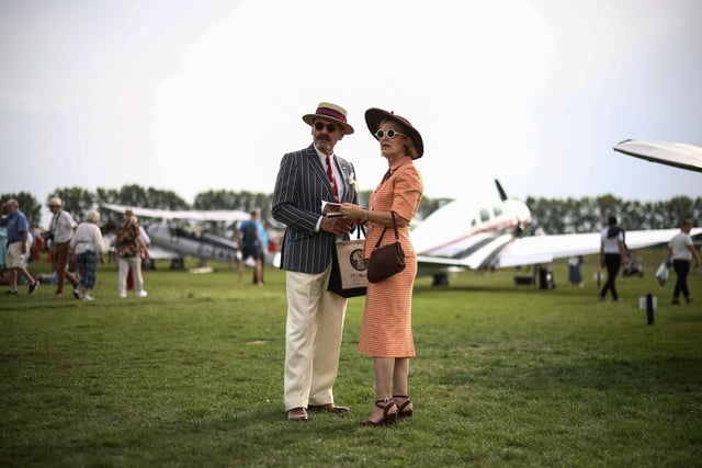 People wearing period clothing attend the opening day of Goodwood Revival at the Goodwood Motor Circuit in Chichester on September 8, 2023. The only historic motor race meeting to be staged entirely in a period theme, Goodwood Revival is an immersive celebration of iconic cars and fashion. 

(Photo by HENRY NICHOLLS/AFP via Getty Images)