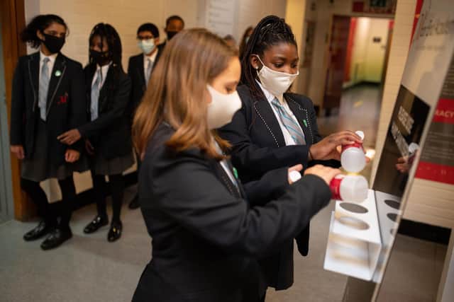 Year eight pupils wearing face masks as a precaution against the transmission of the novel coronavirus sanitise their hands in a corridor at Moor End Academy in Huddersfield, northern England on September 11, 2020. - Millions of children across England have returned to school after the Covid-19 lockdown with many schools introducing measures to enable as safe an environment as possible. (Photo by OLI SCARFF / AFP) (Photo by OLI SCARFF/AFP via Getty Images)