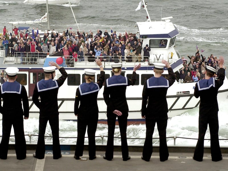 Sailors aboard HMS Ark Royal wave to a civilian vessel full of well wishers welcoming the aircraft carrier home 15th May 2003. Picture: Jonathan Brady 032429-17