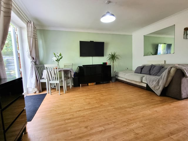 The lounge includes laminate flooring, two radiators, and a door to an understairs storage cupboard.