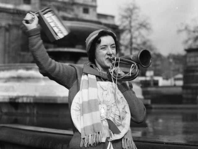 29th April 1939:  A Portsmouth soccer supporter in Trafalgar Square, London blows a horn and waves a rattle. She is in London to watch an FA Cup match.  (Photo by Stephenson/Topical Press Agency/Getty Images)