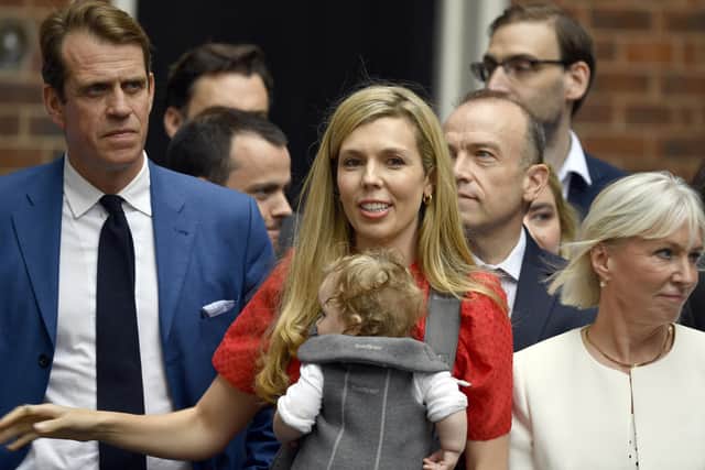 Carrie Johnson, holding daughter Romy, watches Boris Johnson as he reads a statement outside 10 Downing Street