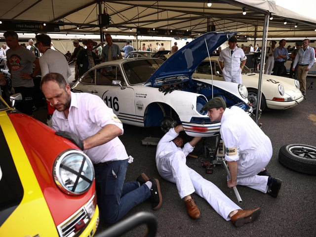 Mechanics repair a classic Porsche following a race during the opening day of Goodwood Revival at the Goodwood Motor Circuit in Chichester on September 8, 2023. The only historic motor race meeting to be staged entirely in a period theme, Goodwood Revival is an immersive celebration of iconic cars and fashion. (Photo by HENRY NICHOLLS / AFP) (Photo by HENRY NICHOLLS/AFP via Getty Images)