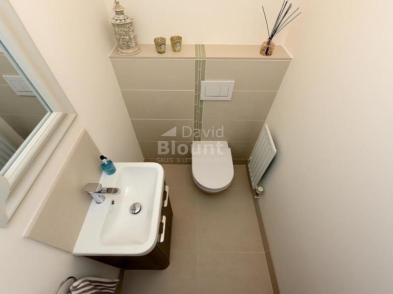 An 'aerial view' of the downstairs cloakroom. It comprises a WC and wash hand basin set with vanity unit, plus radiator and tiled flooring.