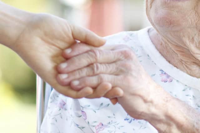 A woman holding hands with a carer.