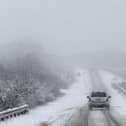 Car drives along snowy road.