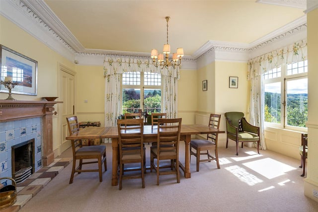 The bright and airy dining room has a feature fireplace and views out to the garden.