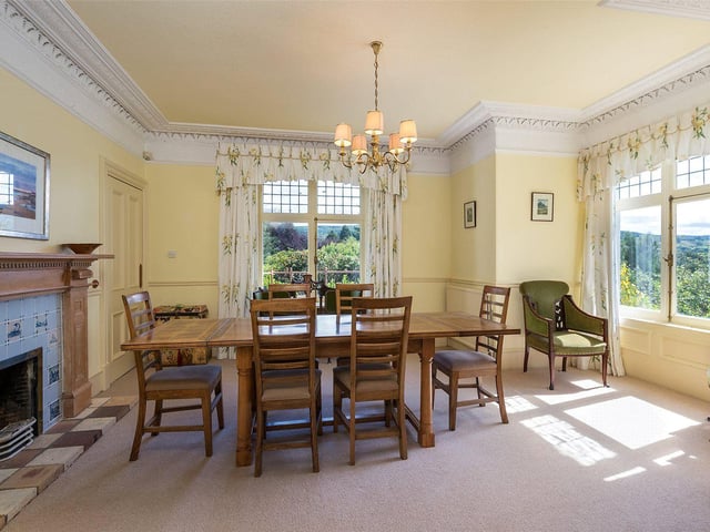 The bright and airy dining room has a feature fireplace and views out to the garden.