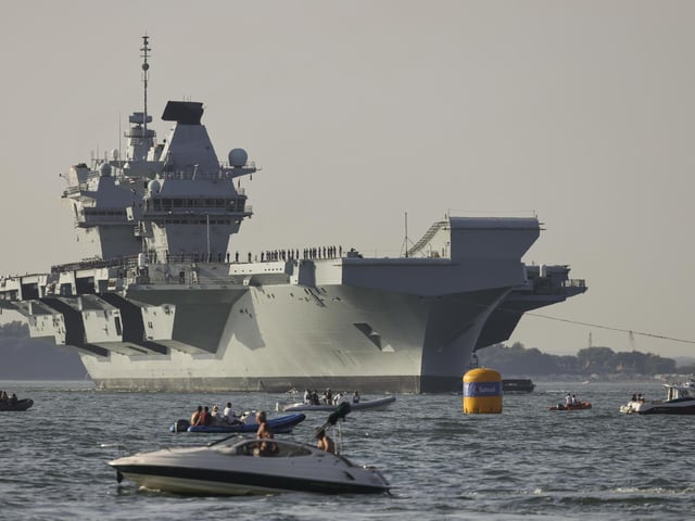 Pictured: HMS Queen Elizabeth enters the Solent off of Cowes and conducts a gun salute in front of the Royal Yacht Squadron.
