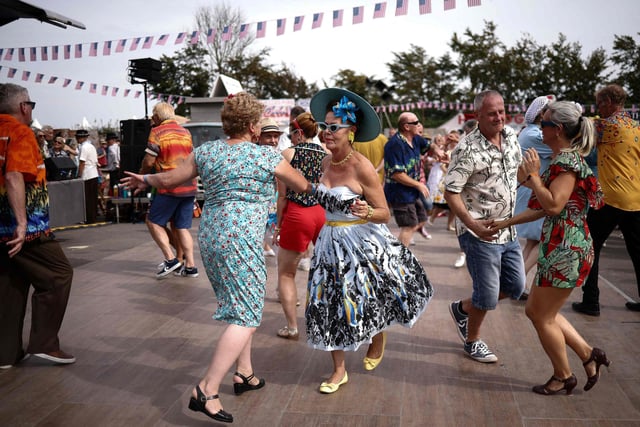 People wearing period clothing dance during the opening day of Goodwood Revival at the Goodwood Motor Circuit in Chichester on September 8, 2023. The only historic motor race meeting to be staged entirely in a period theme, Goodwood Revival is an immersive celebration of iconic cars and fashion. (Photo by HENRY NICHOLLS / AFP) (Photo by HENRY NICHOLLS/AFP via Getty Images)