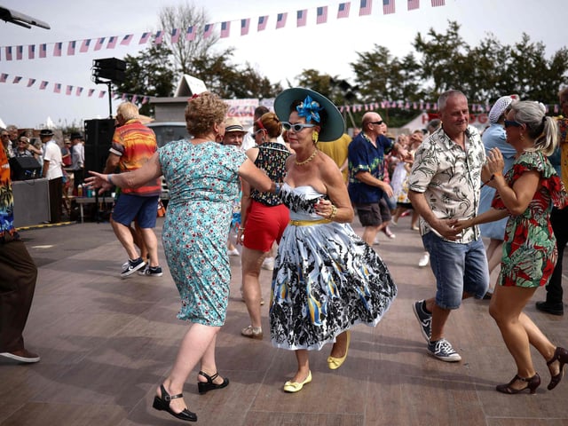 People wearing period clothing dance during the opening day of Goodwood Revival at the Goodwood Motor Circuit in Chichester on September 8, 2023. The only historic motor race meeting to be staged entirely in a period theme, Goodwood Revival is an immersive celebration of iconic cars and fashion. (Photo by HENRY NICHOLLS / AFP) (Photo by HENRY NICHOLLS/AFP via Getty Images)