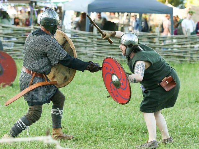A battle re-enactor lands a blow at Beltain Festival at Butser Ancient Farm.