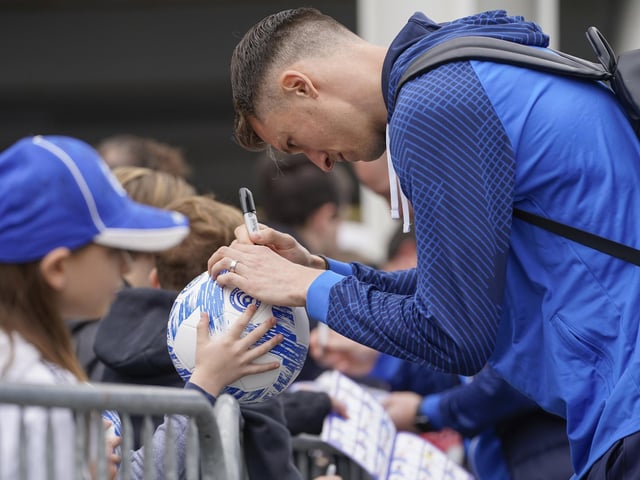 Goalkeeper Matt Macey signs a football for a young fans before taking his place in goal.