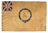 The Kellett sledge flag is made from silk, measures 595 by 885 mm within a frame of 710 by 995mm. The maker is unknown. The motto translates to Help From Above. Picture: NMRN