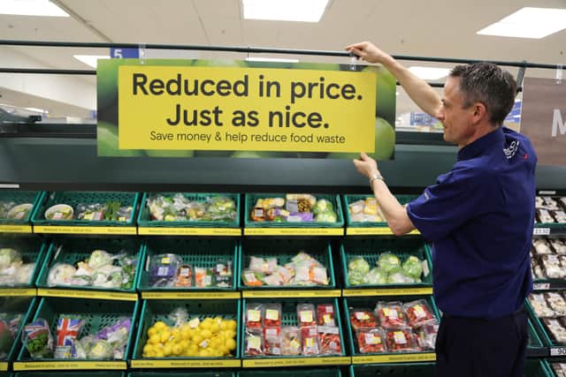 A Tesco employee adjusting a sign as the supermarket is upgrading its 'Reduced to Clear' areas in stores with new, permanent signage amid increasing numbers of customers seeking out the items in an effort to cut costs. Picture: Tesco/PA.