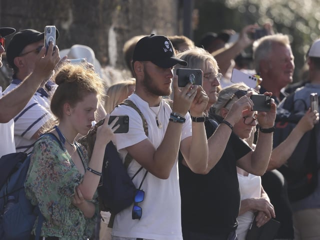 Pictured: Crowds watch on as HMS Queen Elizabeth enters the Solent off of Cowes and conducts a gun salute in front of the Royal Yacht Squadron.
