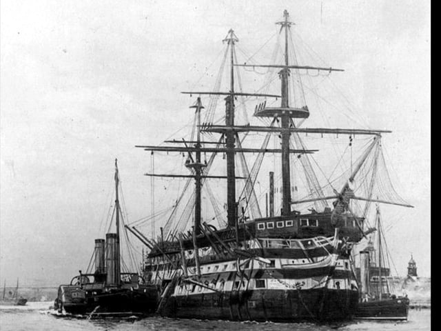 De-masted three decker in Portsmouth Harbour.This marvellous photograph of a Nelsonian/Napolionic wooden wall was loaned to us by William Tofts of Copnor. We don't believe it's HMS Victory, but could be. The steam tugs are assisting alongside.