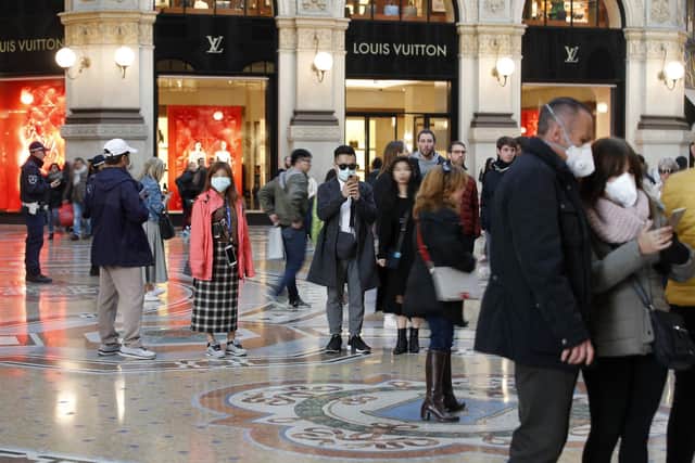 Tourists wearing sanitary masks walk in downtown Milan, Italy. Picture: AP Photo/Antonio Calanni