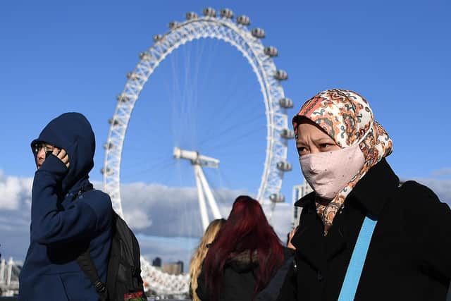 A woman wearing a face mask walks across Westminster Bridge, near the London Eye landmark in central London. Picture: DANIEL LEAL-OLIVAS/AFP via Getty Images