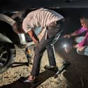 Bishop Jonathan Frost holds a torch as his colleague changes the tyre of their car in Ghana earlier this year