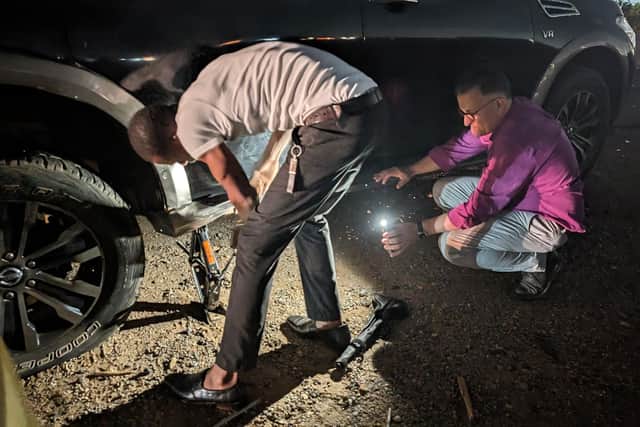 Bishop Jonathan Frost holds a torch as his colleague changes the tyre of their car in Ghana earlier this year